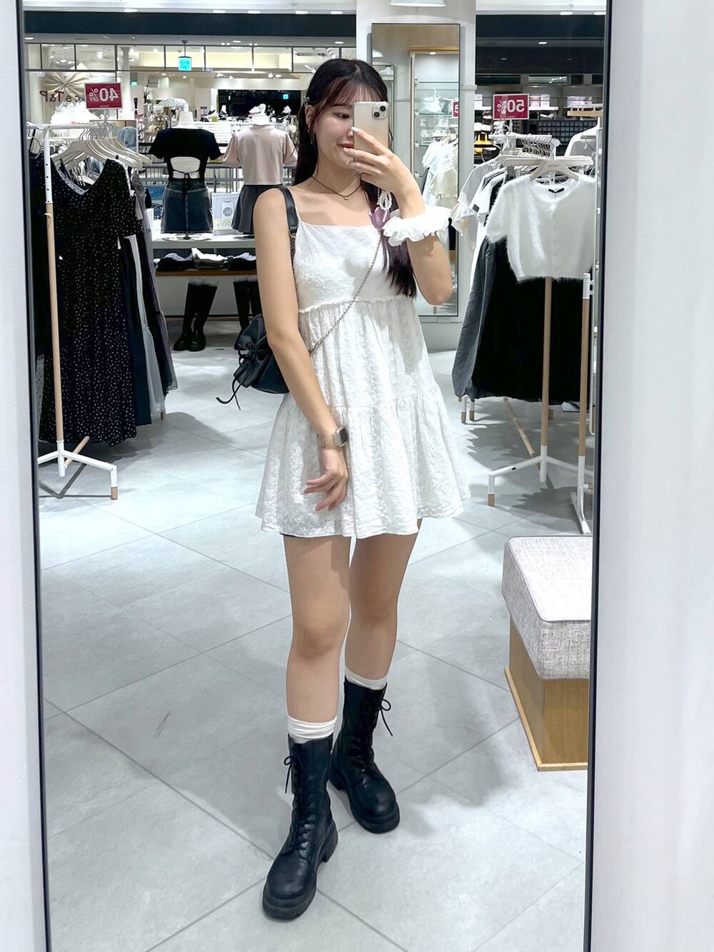 グレー系のショルダーバッグ、ホワイト系のワンピース、ブラック系のブーツを着用したレディースの夏コーディネートの5枚目の写真