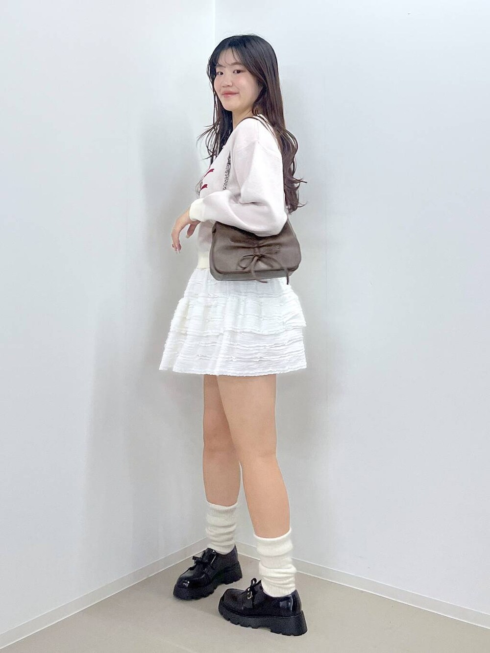ブラウン系のショルダーバッグ、ホワイト系のTシャツ/カットソー、ホワイト系のスカートを着用したレディースの冬コーディネートの2枚目の写真