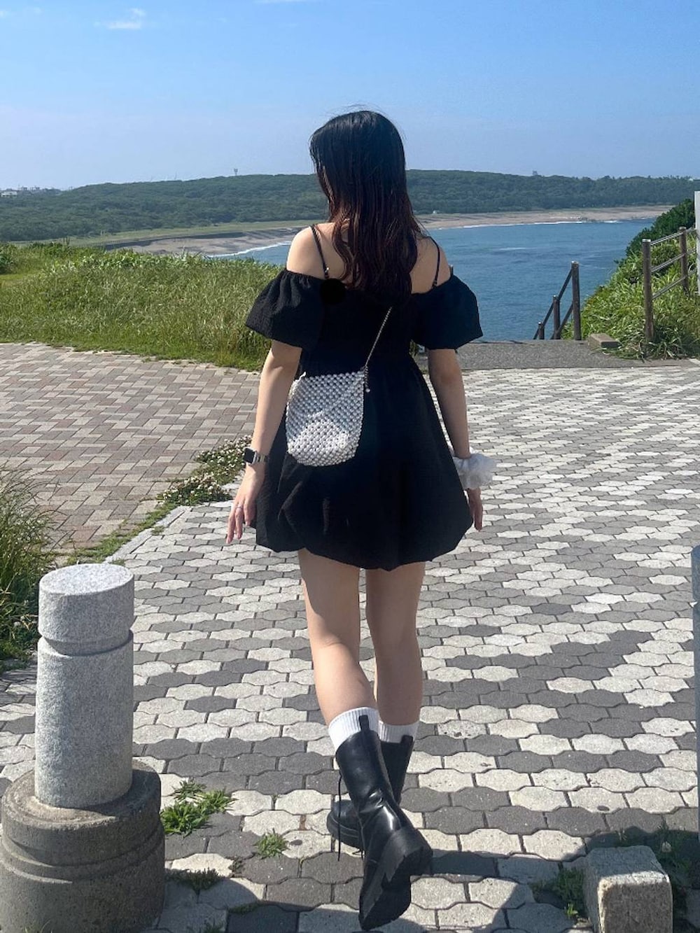 ホワイト系のキャミソール、ブラック系のワンピース、ブラック系のブーツを着用したレディースの夏コーディネートの3枚目の写真