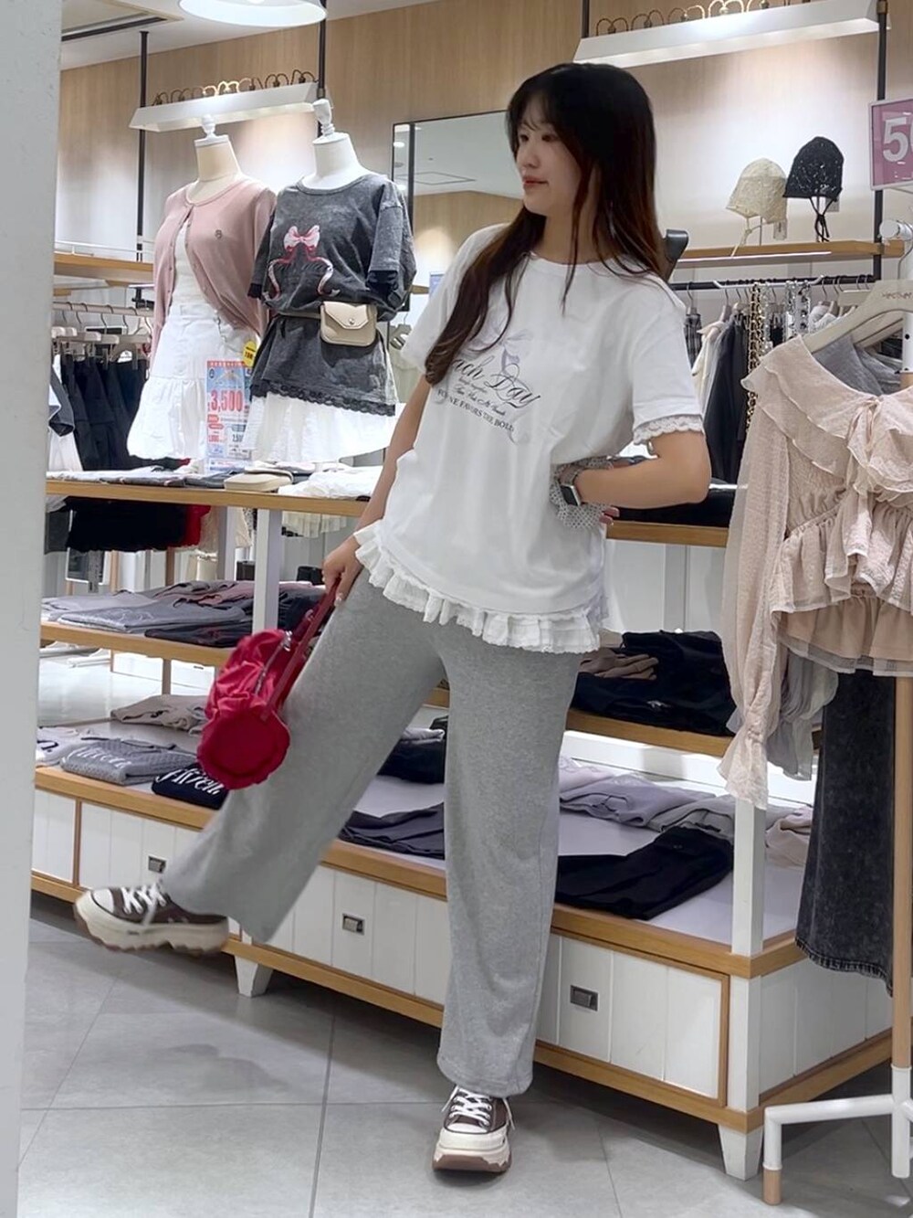 ホワイト系のキャミソール、レッド系のショルダーバッグ、グレー系のスウェットパンツを着用したレディースの春コーディネートの7枚目の写真