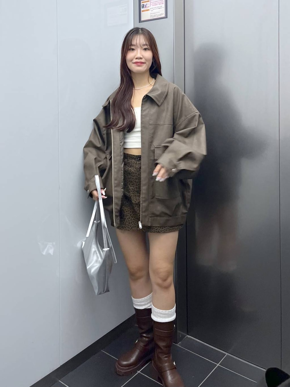ブラウン系のブーツ、その他のスカート、シルバー系のショルダーバッグを着用したレディースの秋コーディネートの5枚目の写真