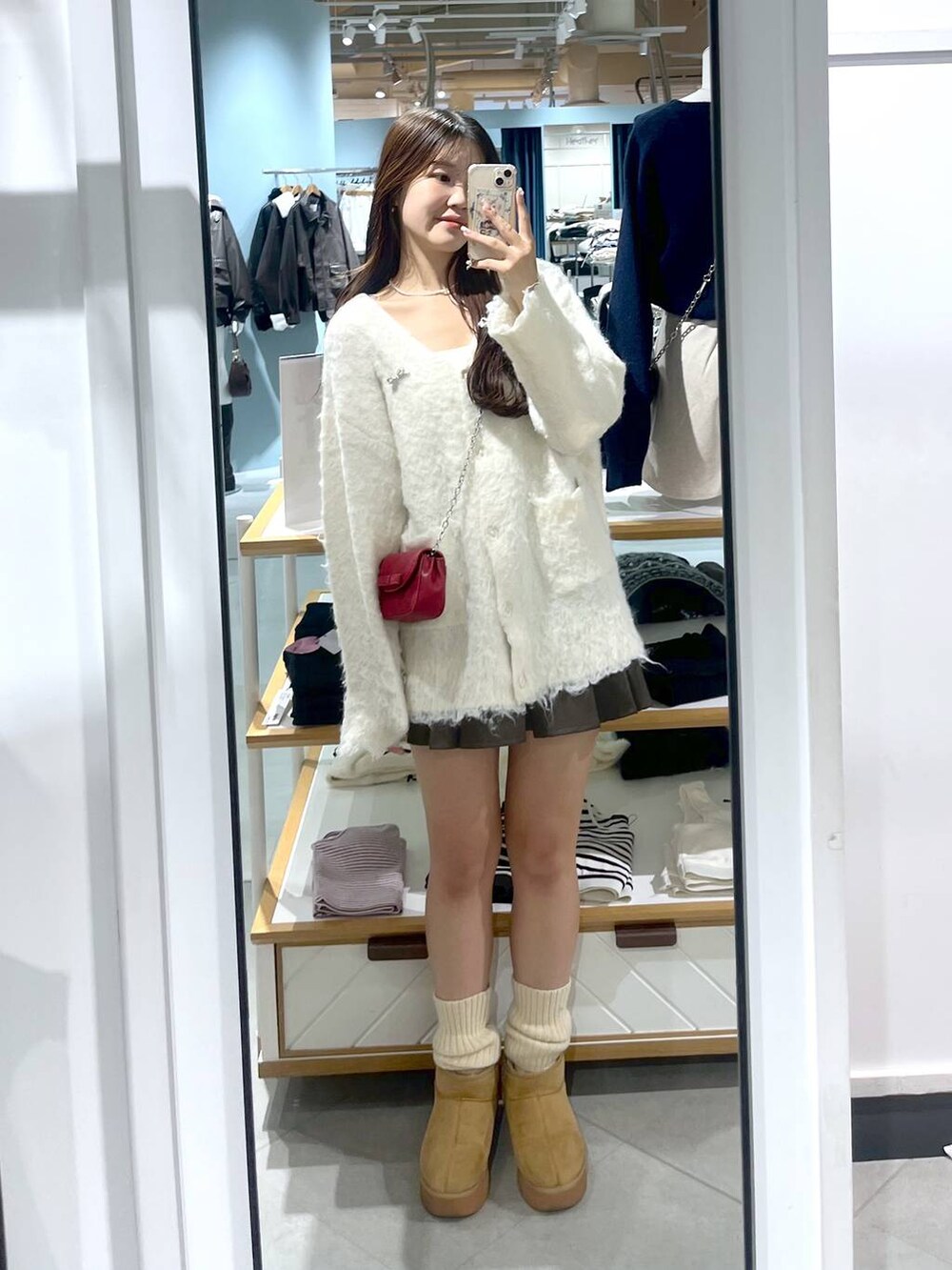 ブラウン系のスカート、ホワイト系のカーディガン/ボレロ、ベージュ系のブーツを着用したレディースの秋コーディネートの2枚目の写真