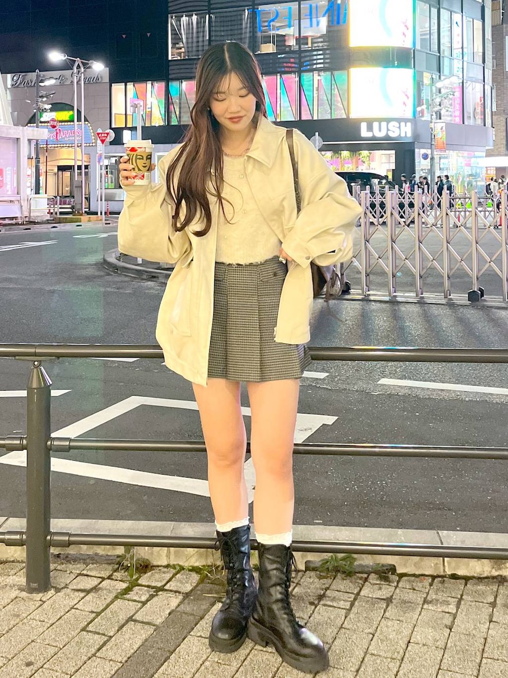 ブラウン系のショルダーバッグ、ベージュ系のスカート、ブラック系のブーツを着用したレディースの秋コーディネートの3枚目の写真