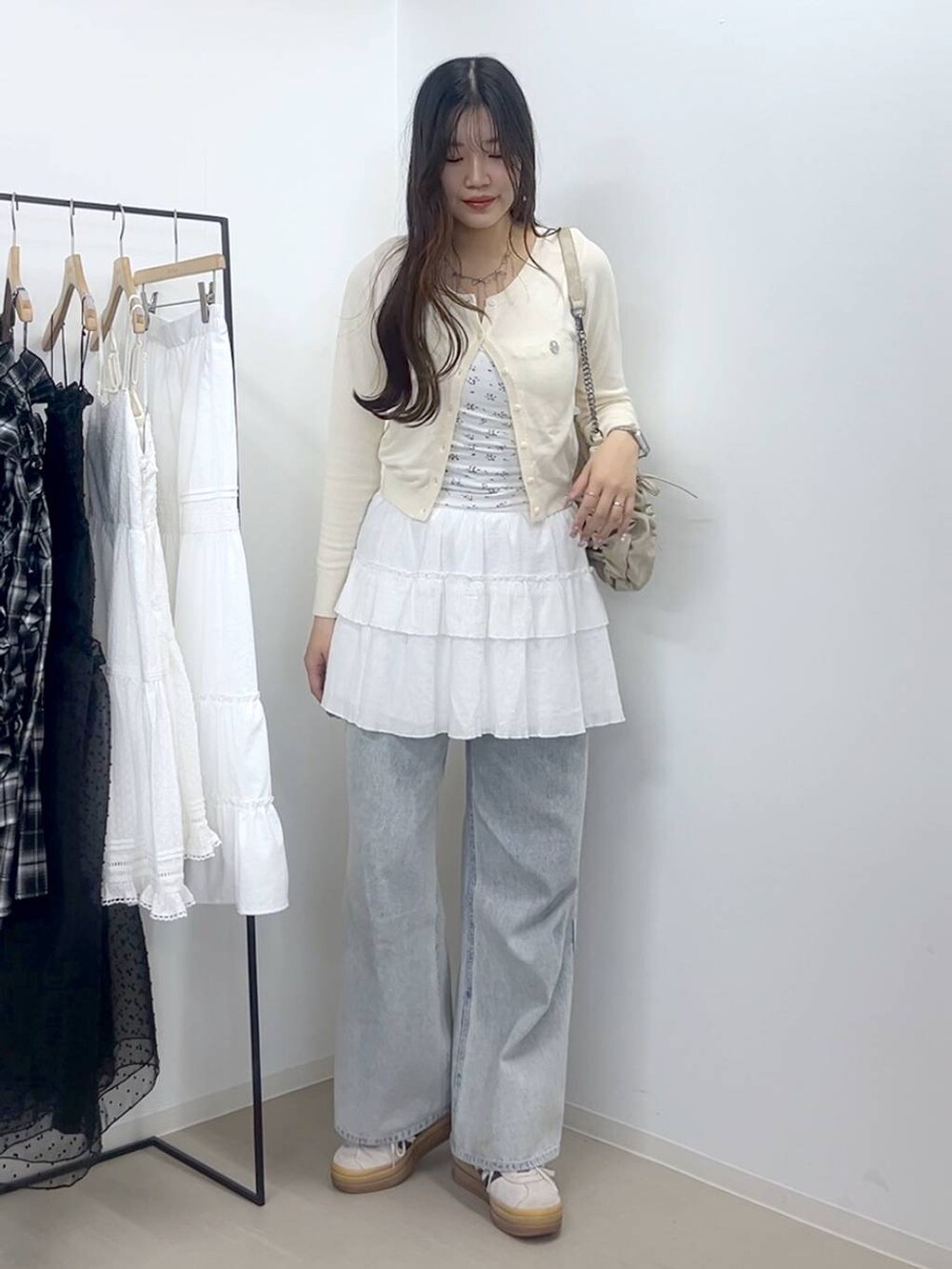 ホワイト系のキャミソール、ブルー系のデニムパンツ、ホワイト系のスカートを着用したレディースの春コーディネートの2枚目の写真