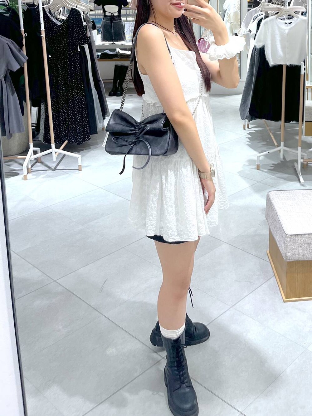 グレー系のショルダーバッグ、ホワイト系のワンピース、ブラック系のブーツを着用したレディースの夏コーディネートの8枚目の写真