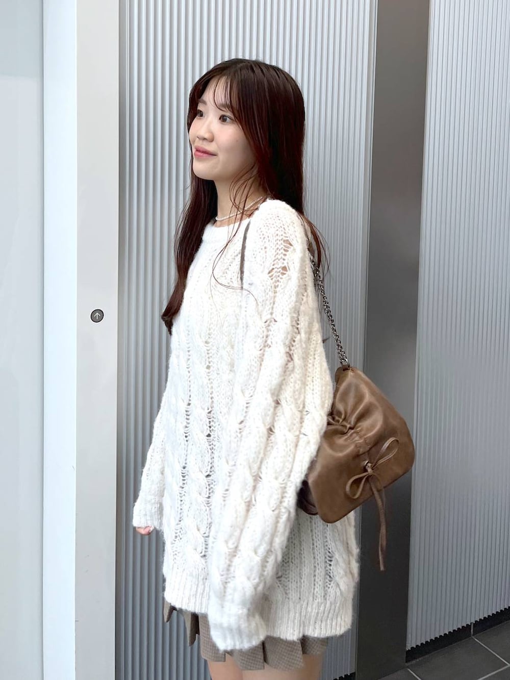 ブラウン系のショルダーバッグ、ブラウン系のブーツ、ホワイト系のキャミソールを着用したレディースの秋コーディネートの4枚目の写真