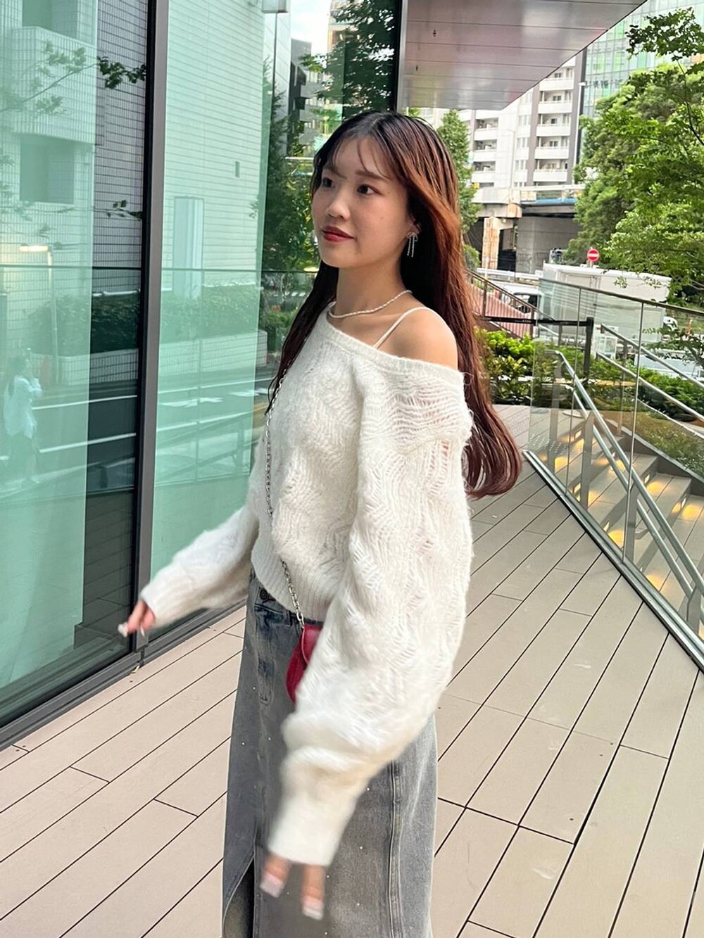 ブルー系のデニムスカート、ホワイト系のキャミソール、レッド系のショルダーバッグを着用したレディースの秋コーディネートの5枚目の写真