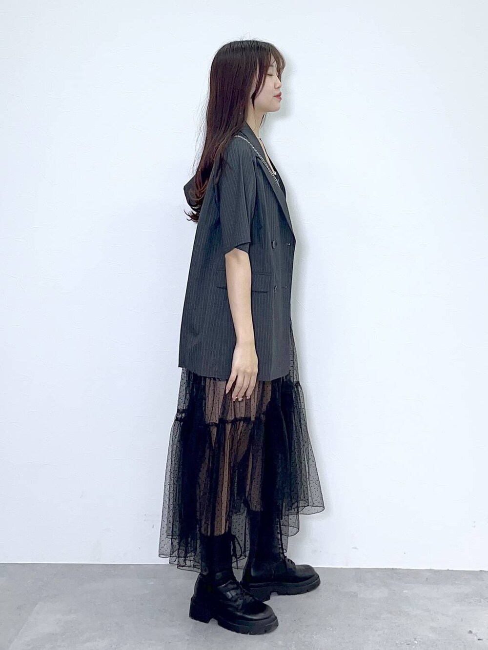 ブラック系のショルダーバッグ、ホワイト系のキャミソール、ブラック系のブーツを着用したレディースの夏コーディネートの2枚目の写真