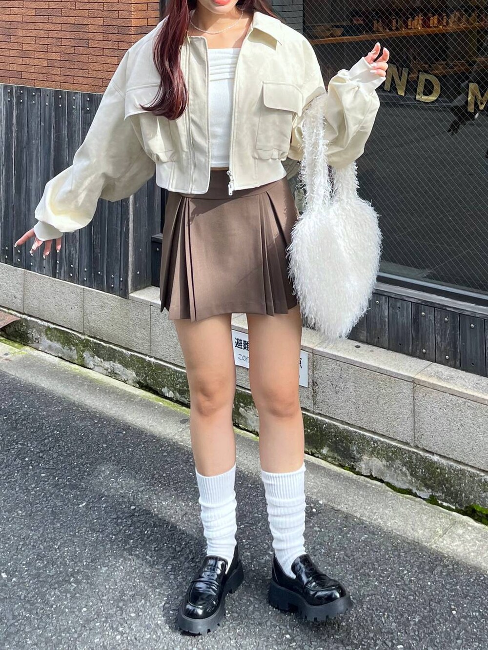 ブラウン系のスカート、ホワイト系のショルダーバッグ、ブラック系のローファーを着用したレディースの秋コーディネートの4枚目の写真