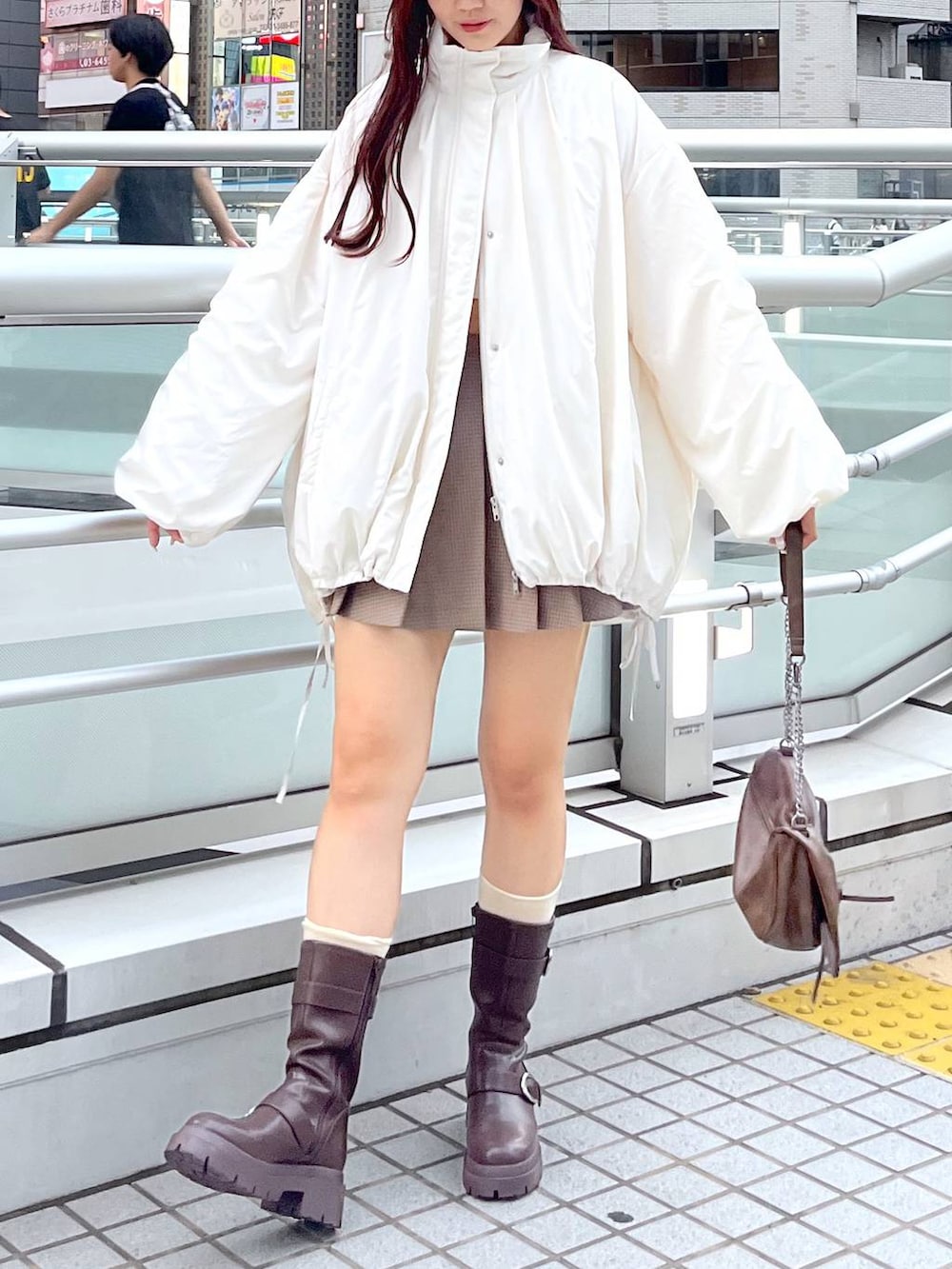 ブラウン系のショルダーバッグ、ブラウン系のブーツ、ホワイト系のキャミソールを着用したレディースの秋コーディネートの3枚目の写真