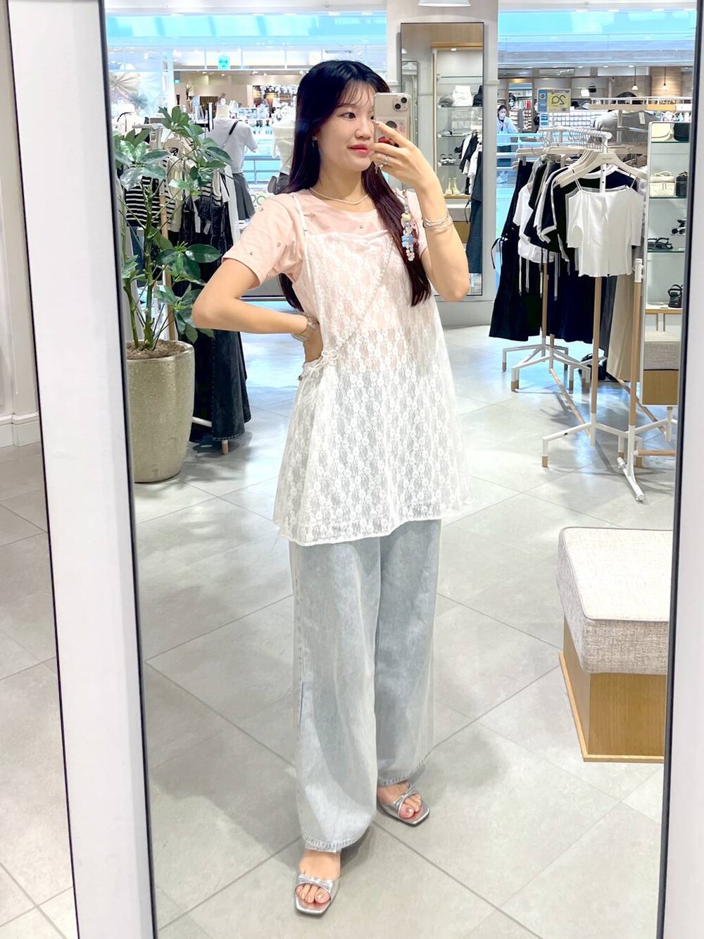 シルバー系のサンダル、ホワイト系のキャミソール、ブルー系のデニムパンツを着用したレディースの春コーディネートの2枚目の写真