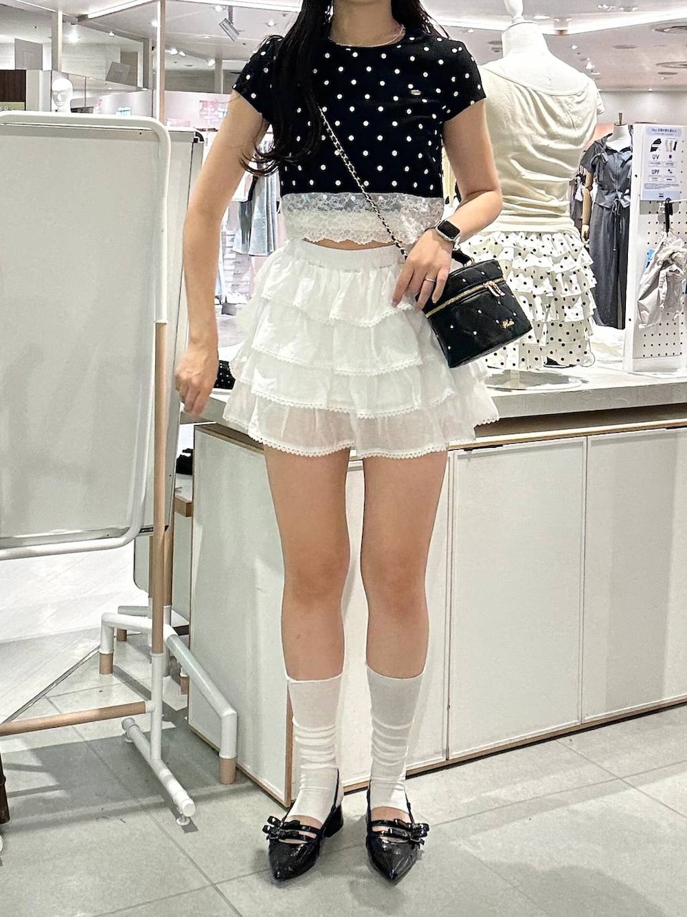 ブラック系のショルダーバッグ、ブラック系のパンプス、ホワイト系のチューブトップを着用したレディースの夏コーディネートの3枚目の写真