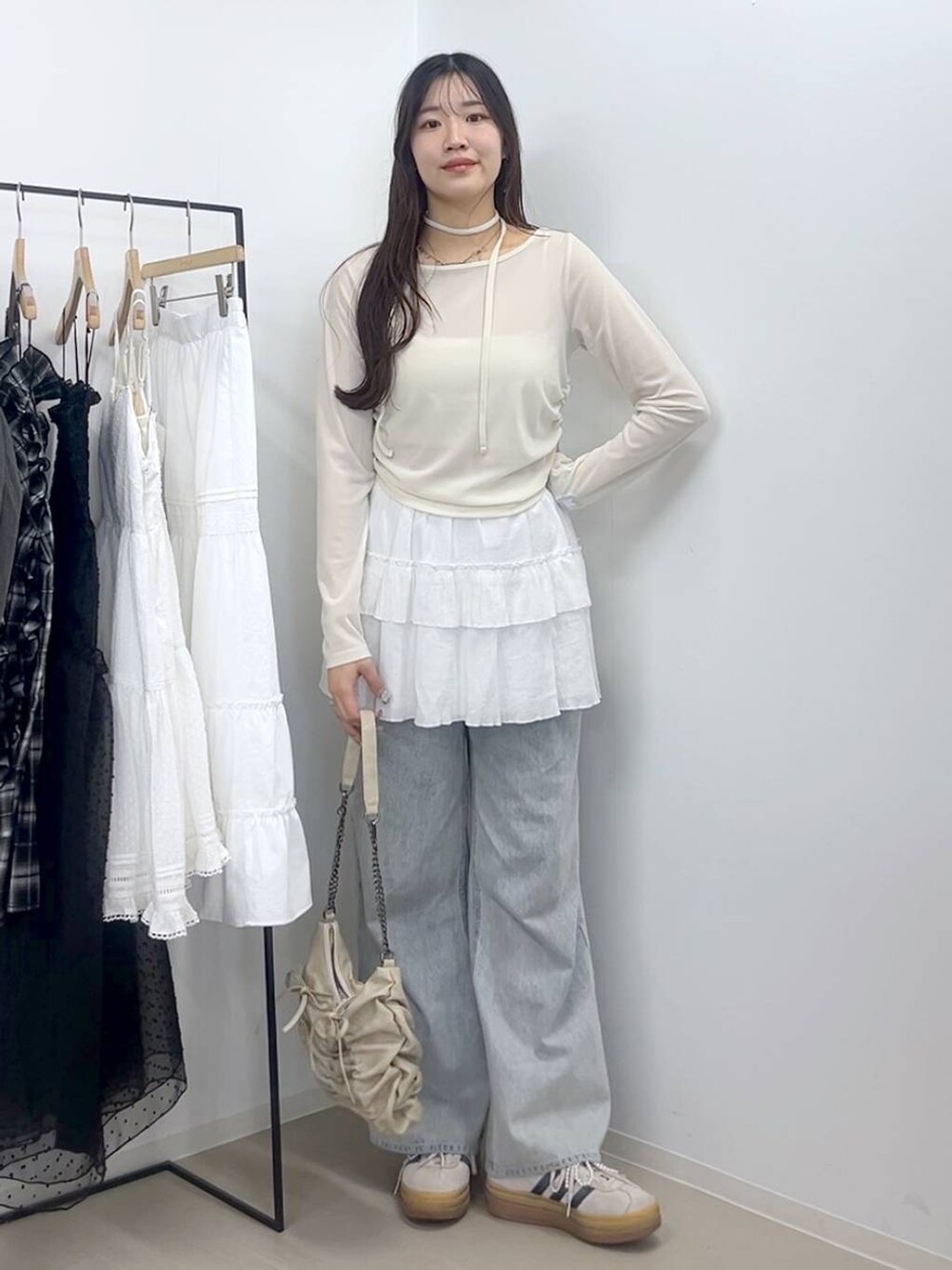 ホワイト系のキャミソール、ブルー系のデニムパンツ、ホワイト系のスカートを着用したレディースの春コーディネートの4枚目の写真