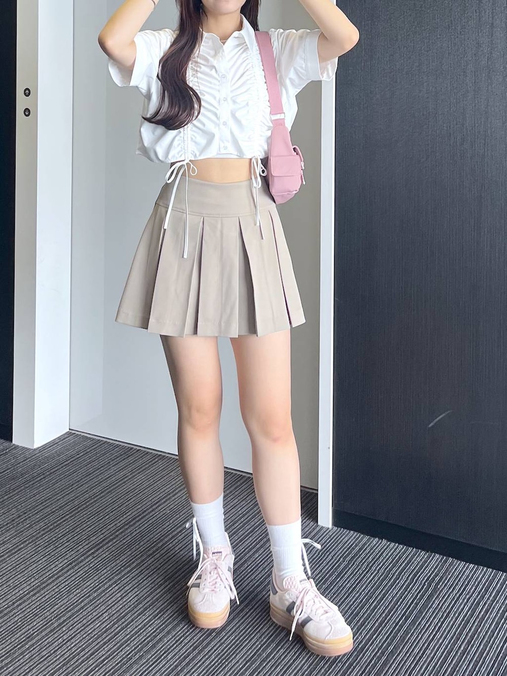 ピンク系のショルダーバッグ、ホワイト系のキャミソール、ベージュ系のスカートを着用したレディースの夏コーディネートの3枚目の写真