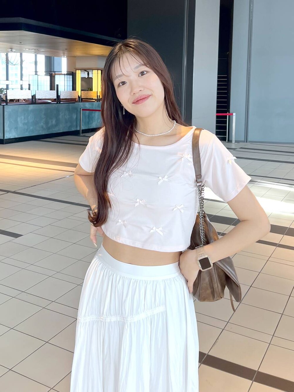 ピンク系のTシャツ/カットソー、ブラウン系のショルダーバッグ、ホワイト系のキャミソールを着用したレディースの春コーディネートの3枚目の写真