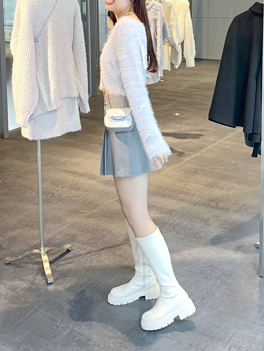 グレー系のスカート、ホワイト系のブーツ、ホワイト系のTシャツ/カットソーを着用したレディースの秋コーディネートの10枚目の写真