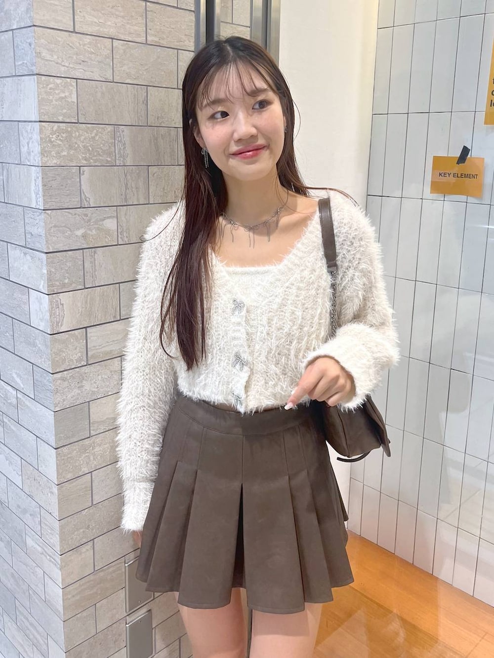 ブラウン系のショルダーバッグ、ホワイト系のアンサンブル、ホワイト系のキャミソールを着用したレディースの秋コーディネートの6枚目の写真