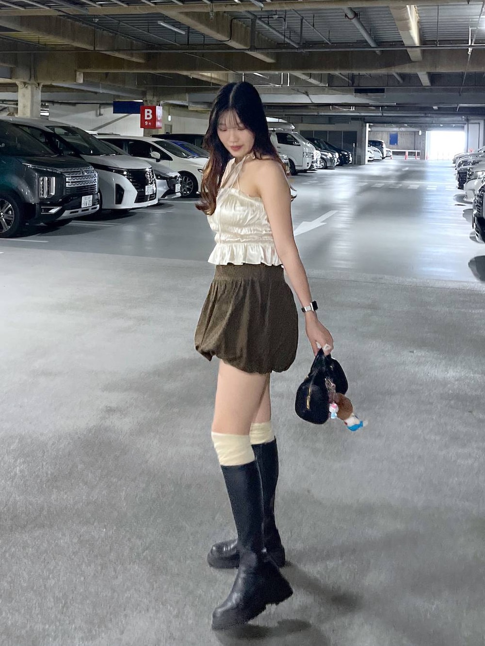 ブラック系のブーツ、ホワイト系のキャミソール、ブラウン系のスカートを着用したレディースの夏コーディネートの6枚目の写真