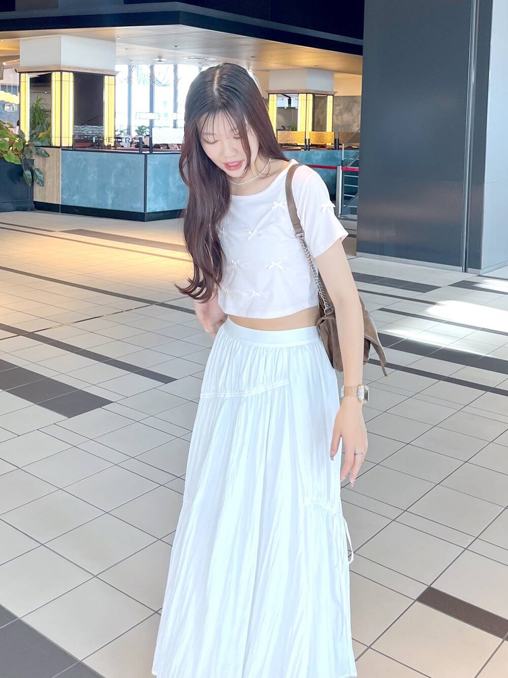 ピンク系のTシャツ/カットソー、ホワイト系のキャミソール、ブラウン系のショルダーバッグを着用したレディースの夏コーディネートの2枚目の写真