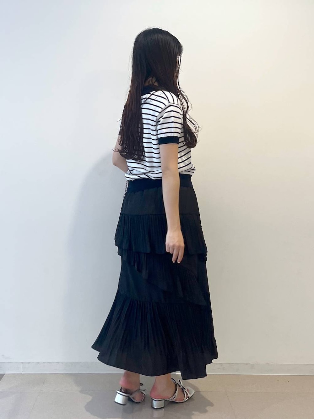 ホワイト系のキャミソール、ブラック系のスカート、シルバー系のサンダルを着用したレディースの春コーディネートの5枚目の写真