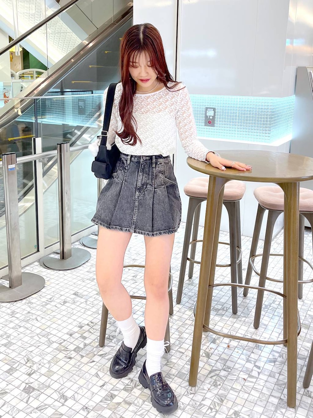 ブラック系のショルダーバッグ、ブラック系のローファー、ブラック系のデニムスカートを着用したレディースの春コーディネートの2枚目の写真