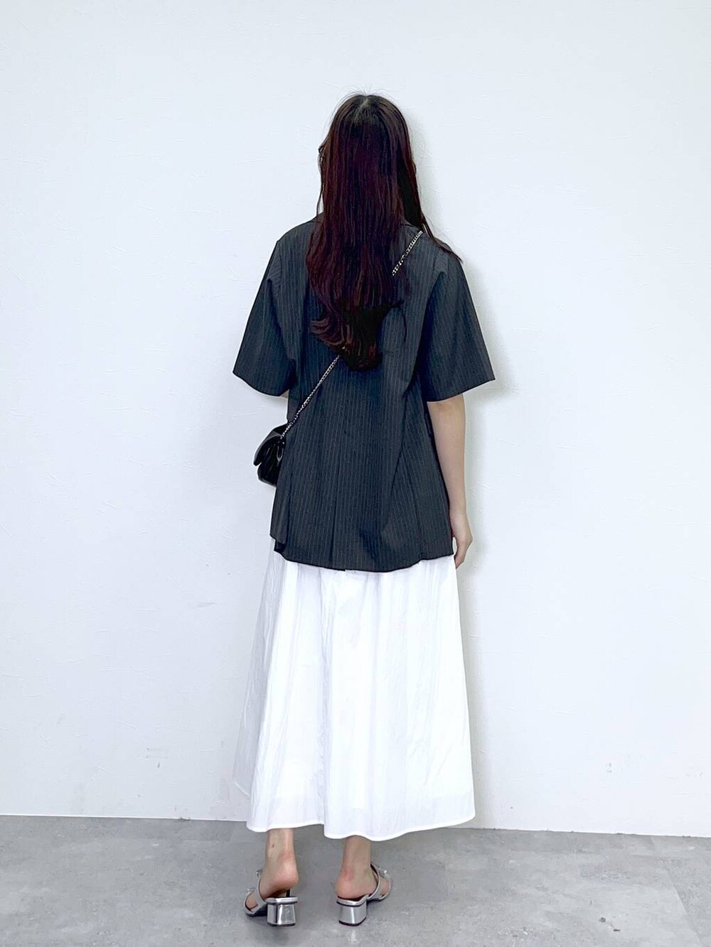 ブラック系のショルダーバッグ、シルバー系のサンダル、ホワイト系のワンピースを着用したレディースの春コーディネートの2枚目の写真