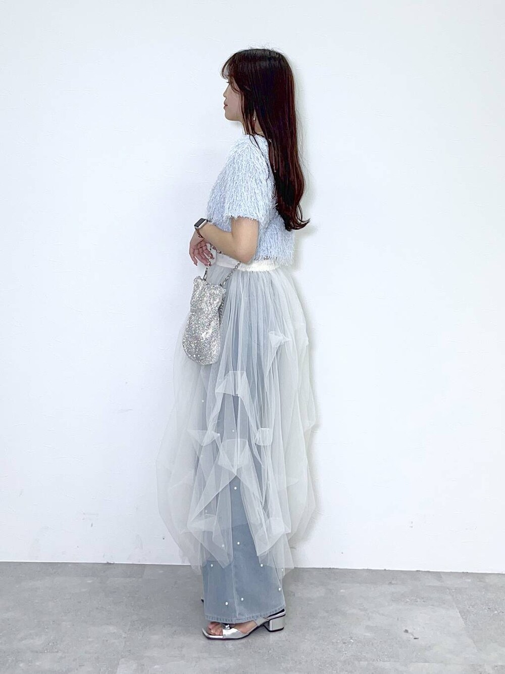 シルバー系のショルダーバッグ、ブルー系のデニムパンツ、ホワイト系のキャミソールを着用したレディースの春コーディネートの3枚目の写真