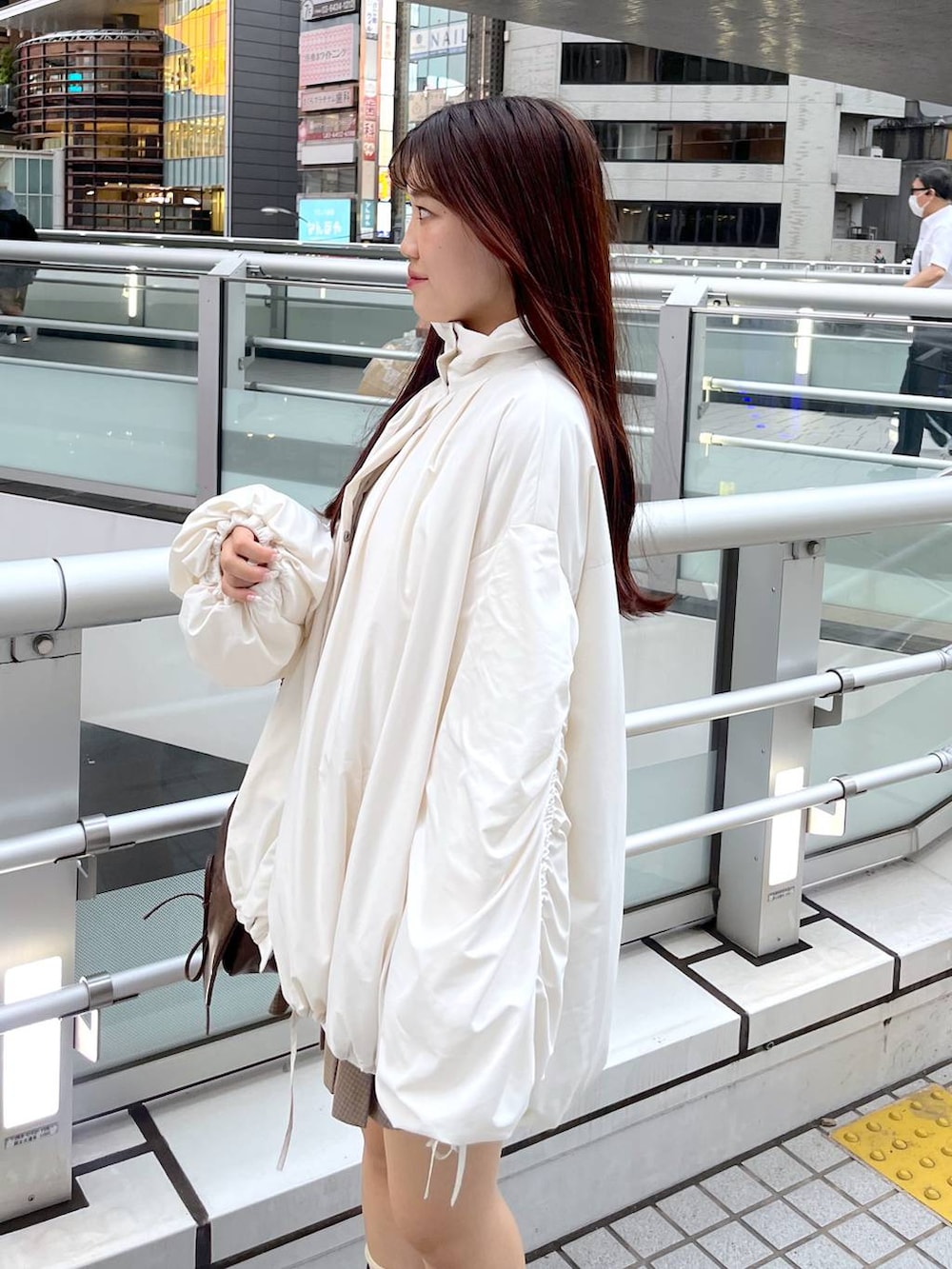 ブラウン系のショルダーバッグ、ブラウン系のブーツ、ホワイト系のキャミソールを着用したレディースの秋コーディネートの2枚目の写真