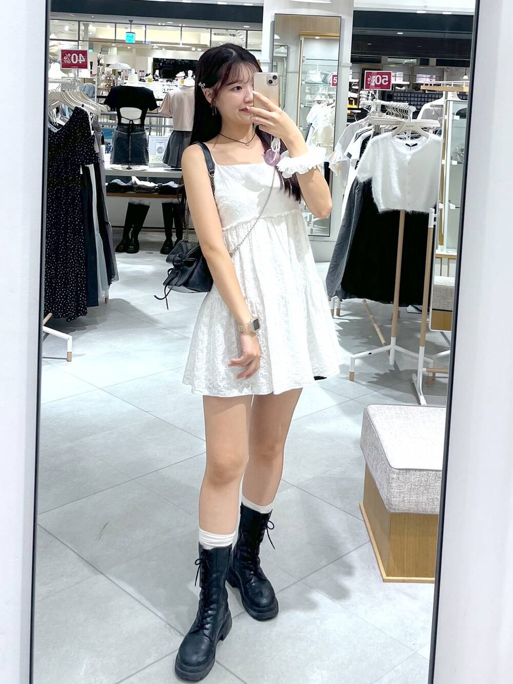 グレー系のショルダーバッグ、ホワイト系のワンピース、ブラック系のブーツを着用したレディースの夏コーディネートの3枚目の写真