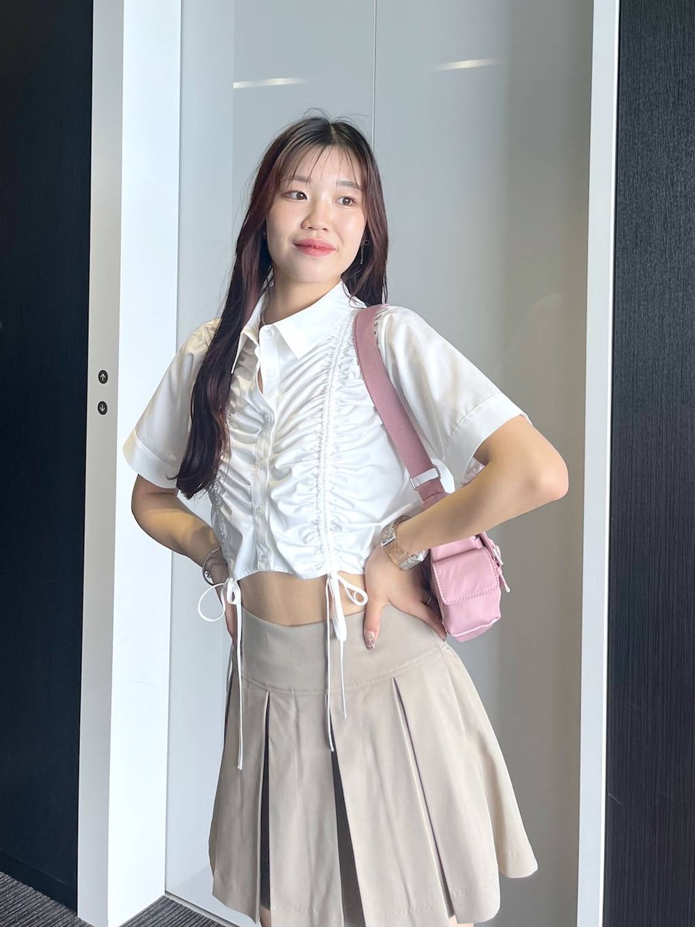 ピンク系のショルダーバッグ、ホワイト系のキャミソール、ベージュ系のスカートを着用したレディースの夏コーディネートの2枚目の写真