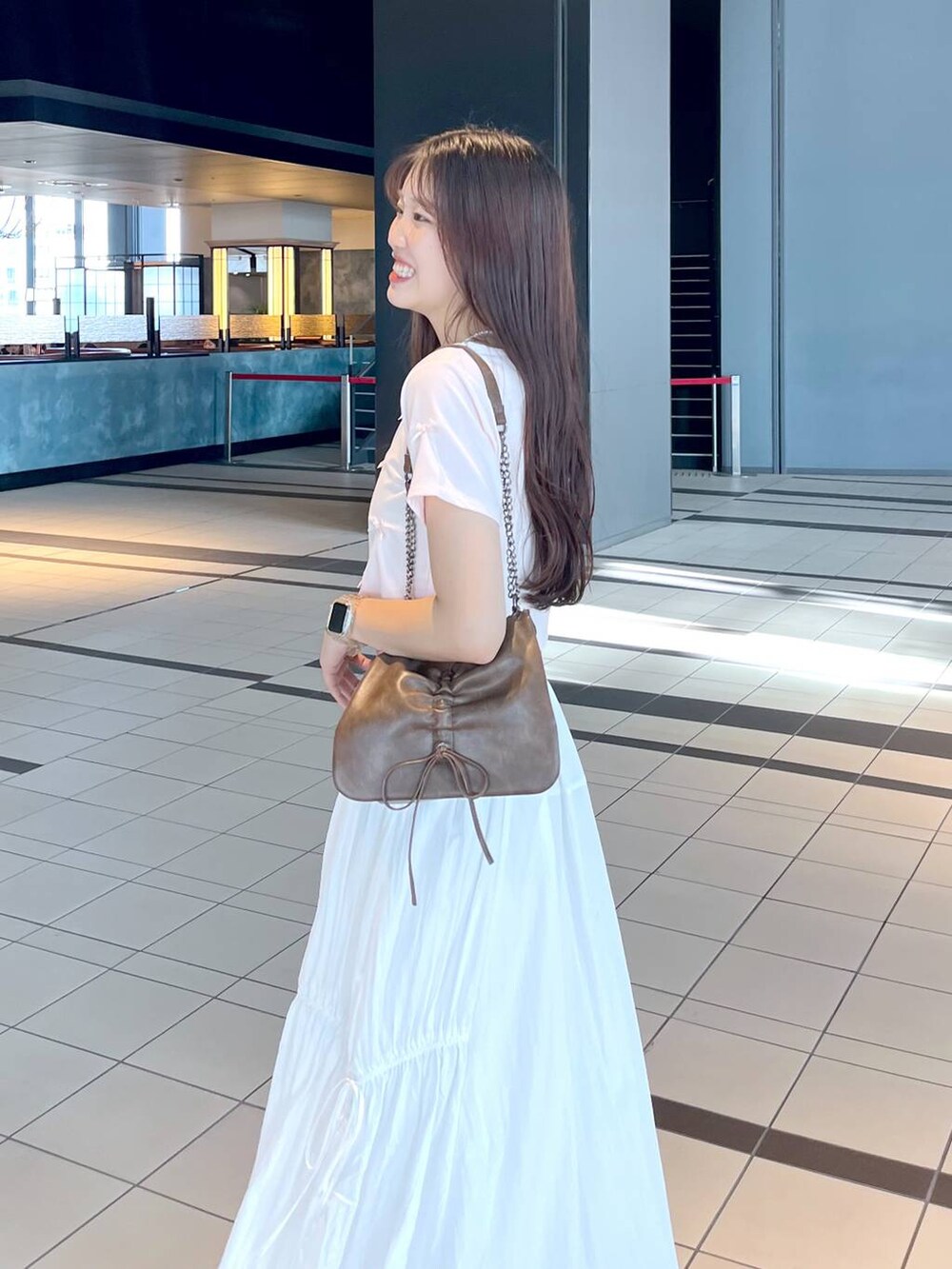 ピンク系のTシャツ/カットソー、ブラウン系のショルダーバッグ、ホワイト系のキャミソールを着用したレディースの春コーディネートの4枚目の写真