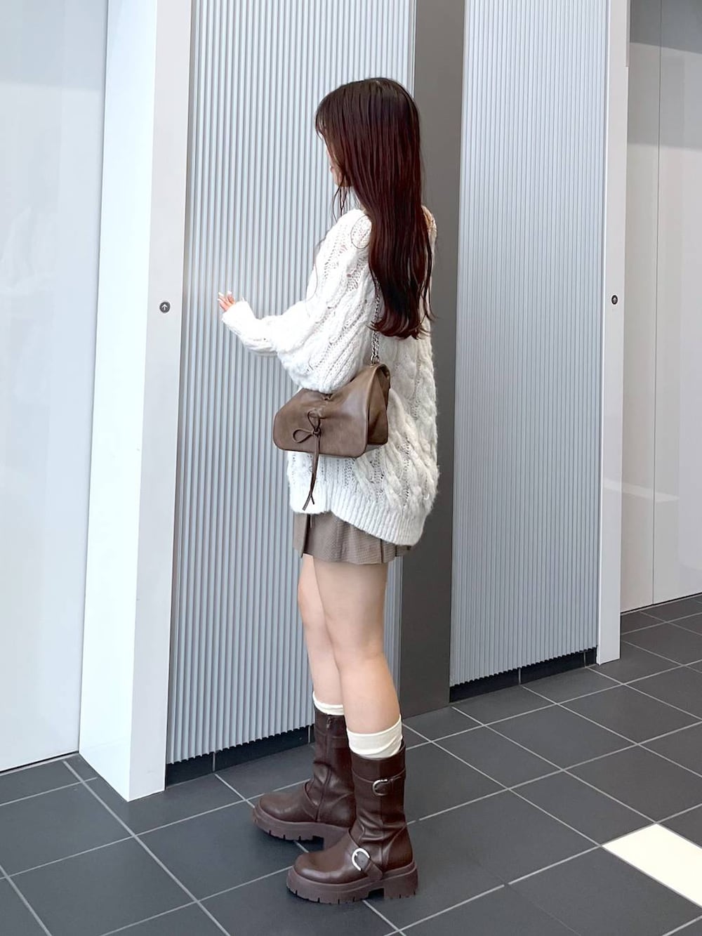 ブラウン系のショルダーバッグ、ブラウン系のブーツ、ホワイト系のキャミソールを着用したレディースの秋コーディネートの7枚目の写真