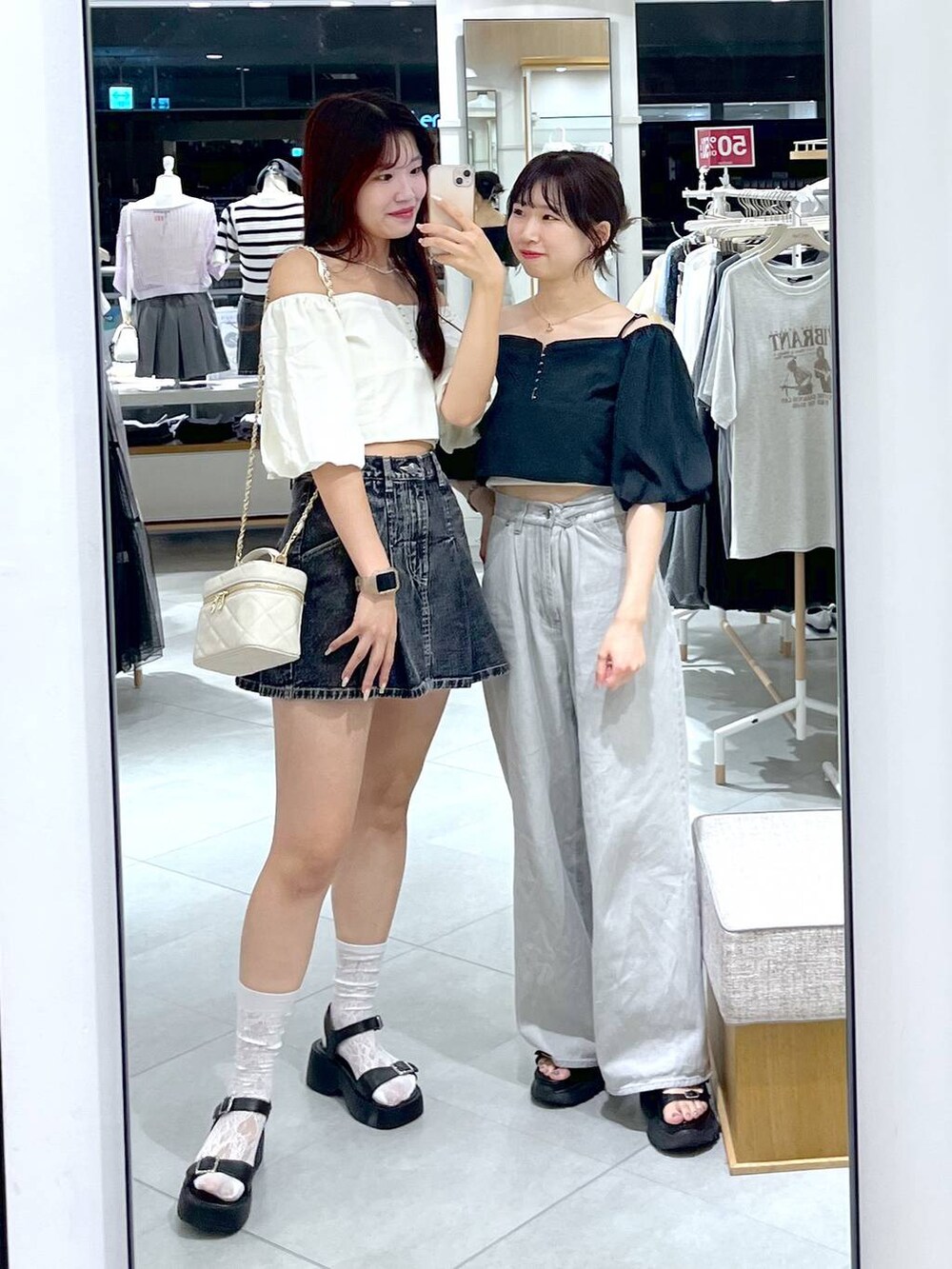 ブラック系のデニムスカート、ブラック系のサンダル、ホワイト系のショルダーバッグを着用したレディースの夏コーディネートの2枚目の写真