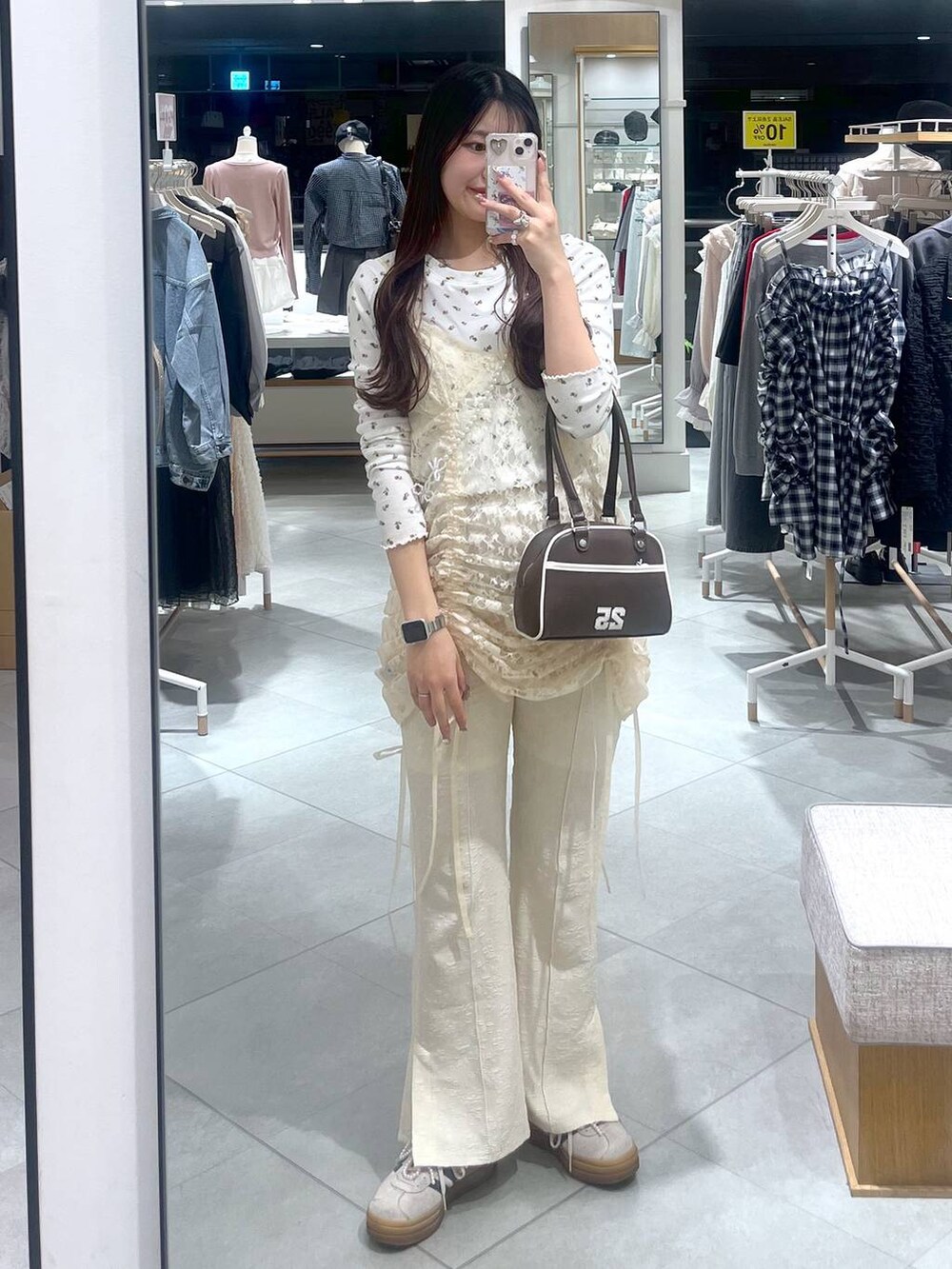 ベージュ系のワンピース、ブラウン系のボストンバッグ、ホワイト系のスマホグッズを着用したレディースの春コーディネートの6枚目の写真