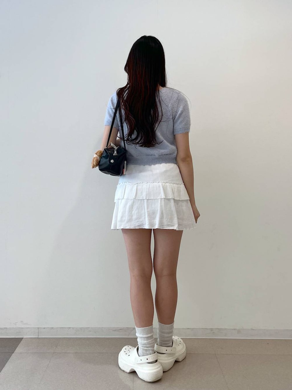 ホワイト系のスカート、ブラック系のボストンバッグ、ホワイト系のキャミソールを着用したレディースの春コーディネートの4枚目の写真