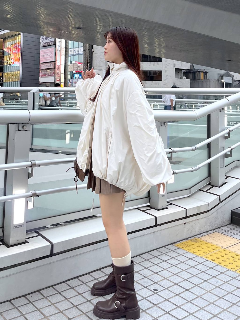 ブラウン系のショルダーバッグ、ブラウン系のブーツ、ホワイト系のキャミソールを着用したレディースの秋コーディネートの6枚目の写真