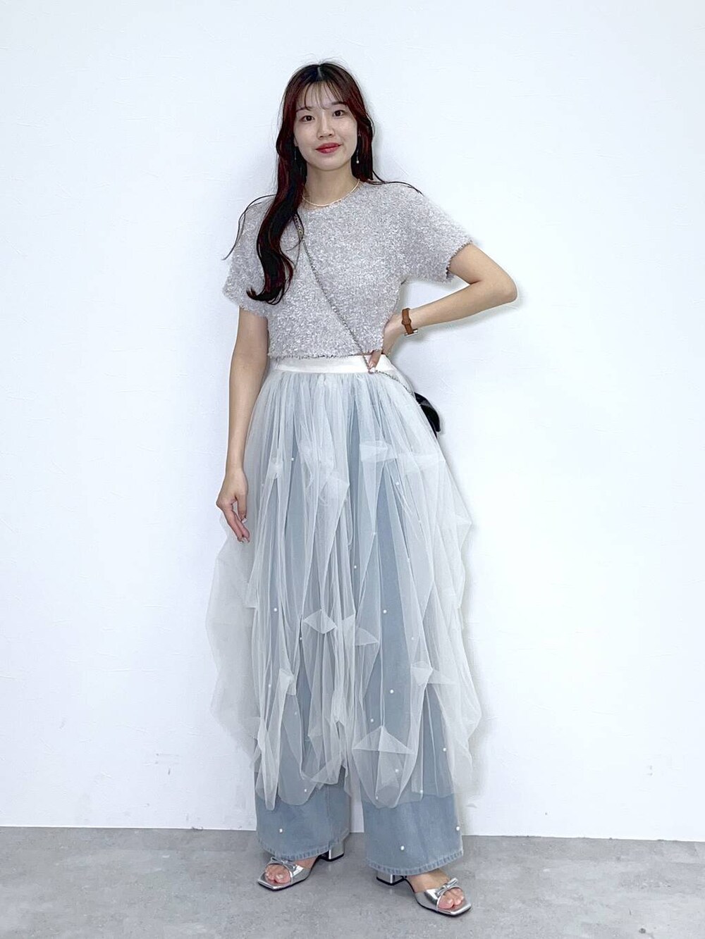 ブラック系のショルダーバッグ、ブルー系のデニムパンツ、ホワイト系のキャミソールを着用したレディースの春コーディネートの2枚目の写真