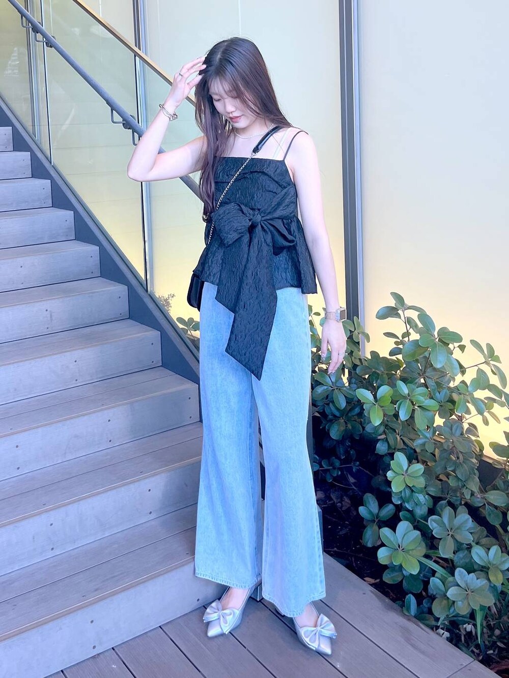 シルバー系のサンダル、ブラック系のショルダーバッグ、ホワイト系のキャミソールを着用したレディースの夏コーディネートの2枚目の写真