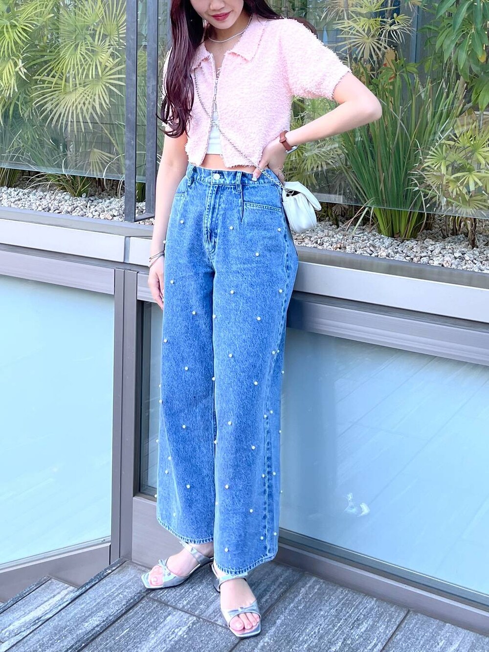 ホワイト系のショルダーバッグ、ホワイト系のキャミソール、ブルー系のデニムパンツを着用したレディースの夏コーディネートの5枚目の写真