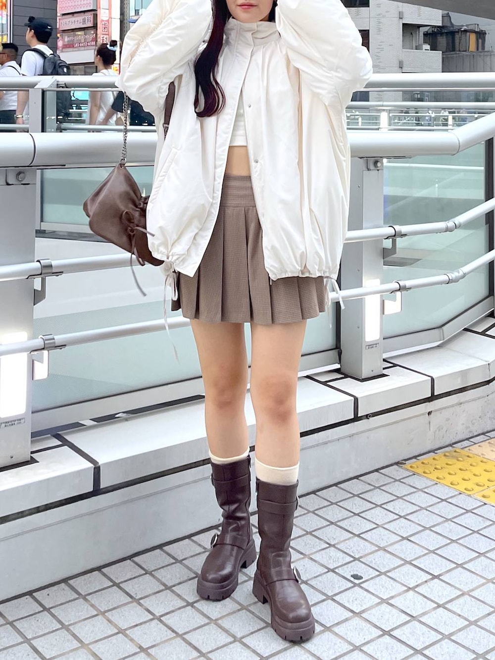 ブラウン系のショルダーバッグ、ブラウン系のブーツ、ホワイト系のキャミソールを着用したレディースの秋コーディネートの4枚目の写真