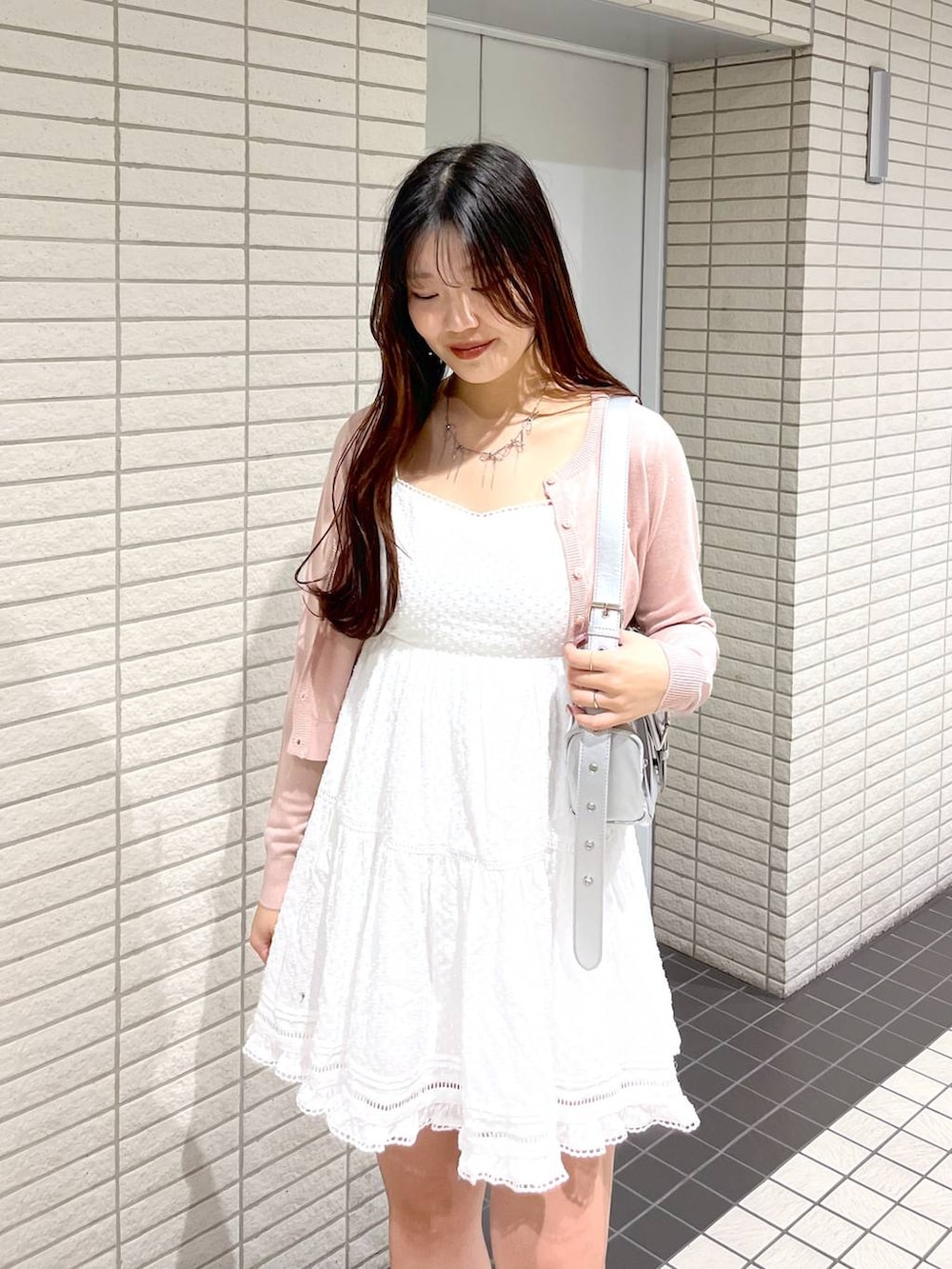 ホワイト系のキャミソール、ピンク系のカーディガン/ボレロ、ブラック系のブーツを着用したレディースの春コーディネートの6枚目の写真