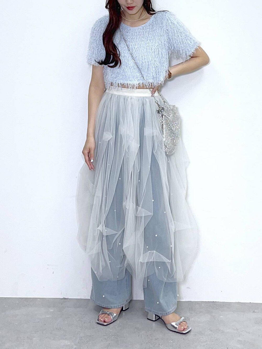 シルバー系のショルダーバッグ、ブルー系のデニムパンツ、ホワイト系のキャミソールを着用したレディースの春コーディネートの6枚目の写真