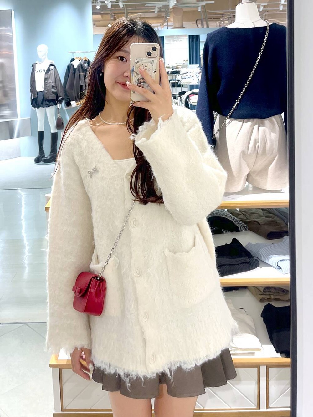 ブラウン系のスカート、ホワイト系のカーディガン/ボレロ、ベージュ系のブーツを着用したレディースの秋コーディネートの6枚目の写真