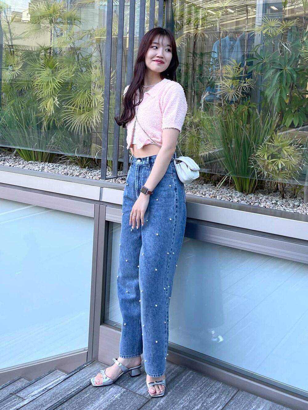 ホワイト系のショルダーバッグ、ホワイト系のキャミソール、ブルー系のデニムパンツを着用したレディースの春コーディネートの4枚目の写真