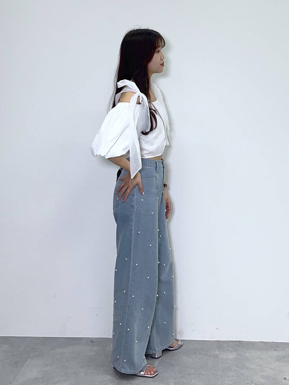 ブラック系のショルダーバッグ、ホワイト系のキャミソール、ブルー系のデニムパンツを着用したレディースの夏コーディネートの4枚目の写真