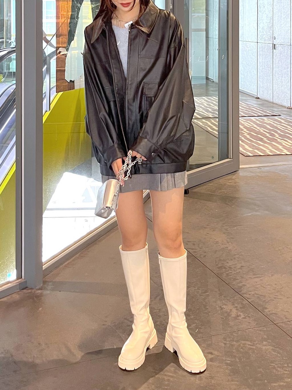 グレー系のスカート、ホワイト系のブーツ、ブラック系のブルゾンを着用したレディースの秋コーディネートの4枚目の写真