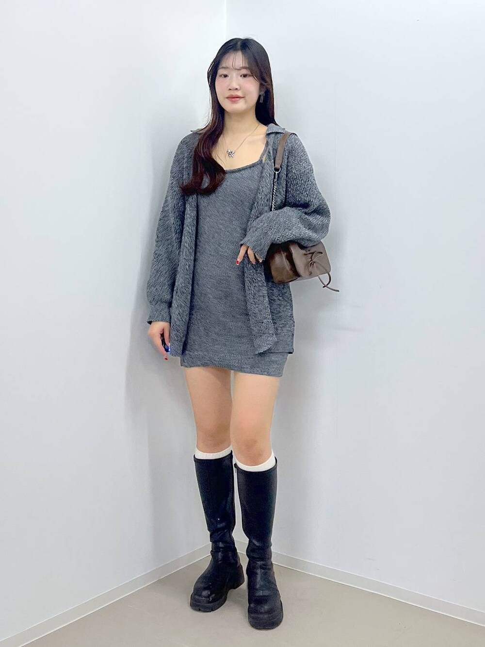 ブラウン系のショルダーバッグ、ホワイト系のキャミソール、ブラック系のブーツを着用したレディースの春コーディネートの2枚目の写真