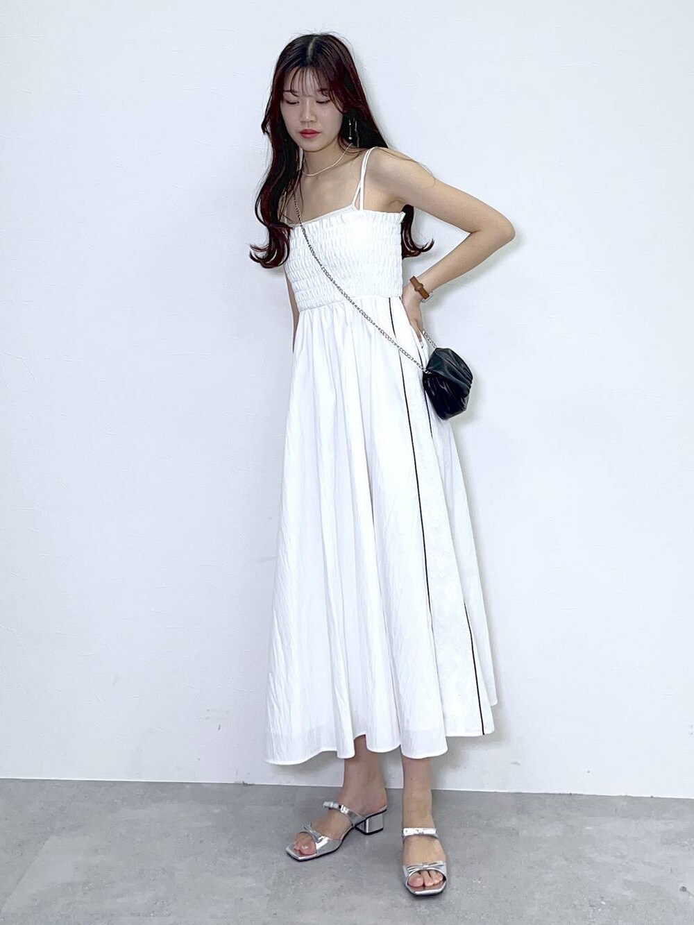 ブラック系のショルダーバッグ、シルバー系のサンダル、ホワイト系のワンピースを着用したレディースの夏コーディネートの6枚目の写真