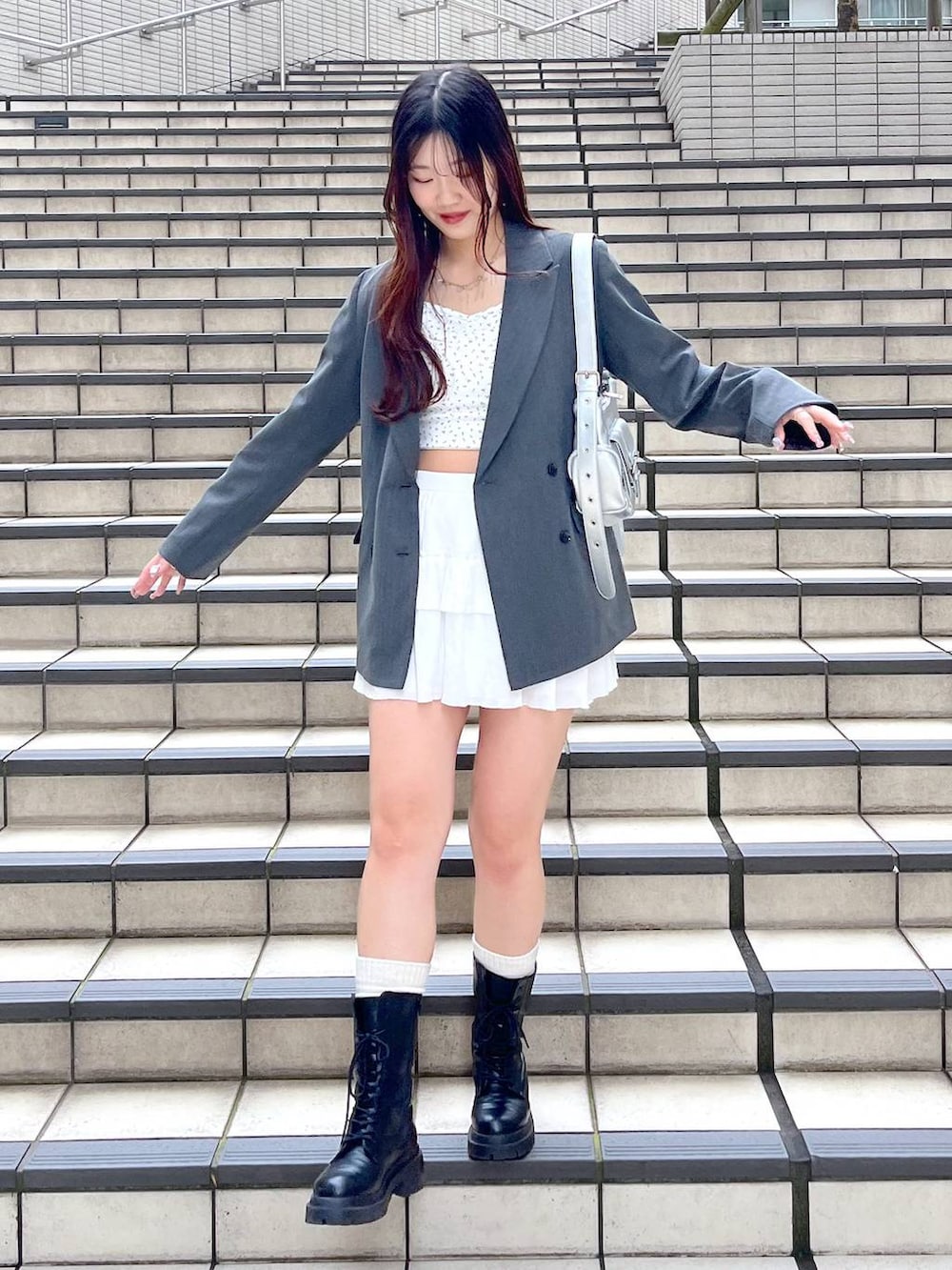 ホワイト系のキャミソール、ホワイト系のスカート、ブラック系のブーツを着用したレディースの春コーディネートの2枚目の写真