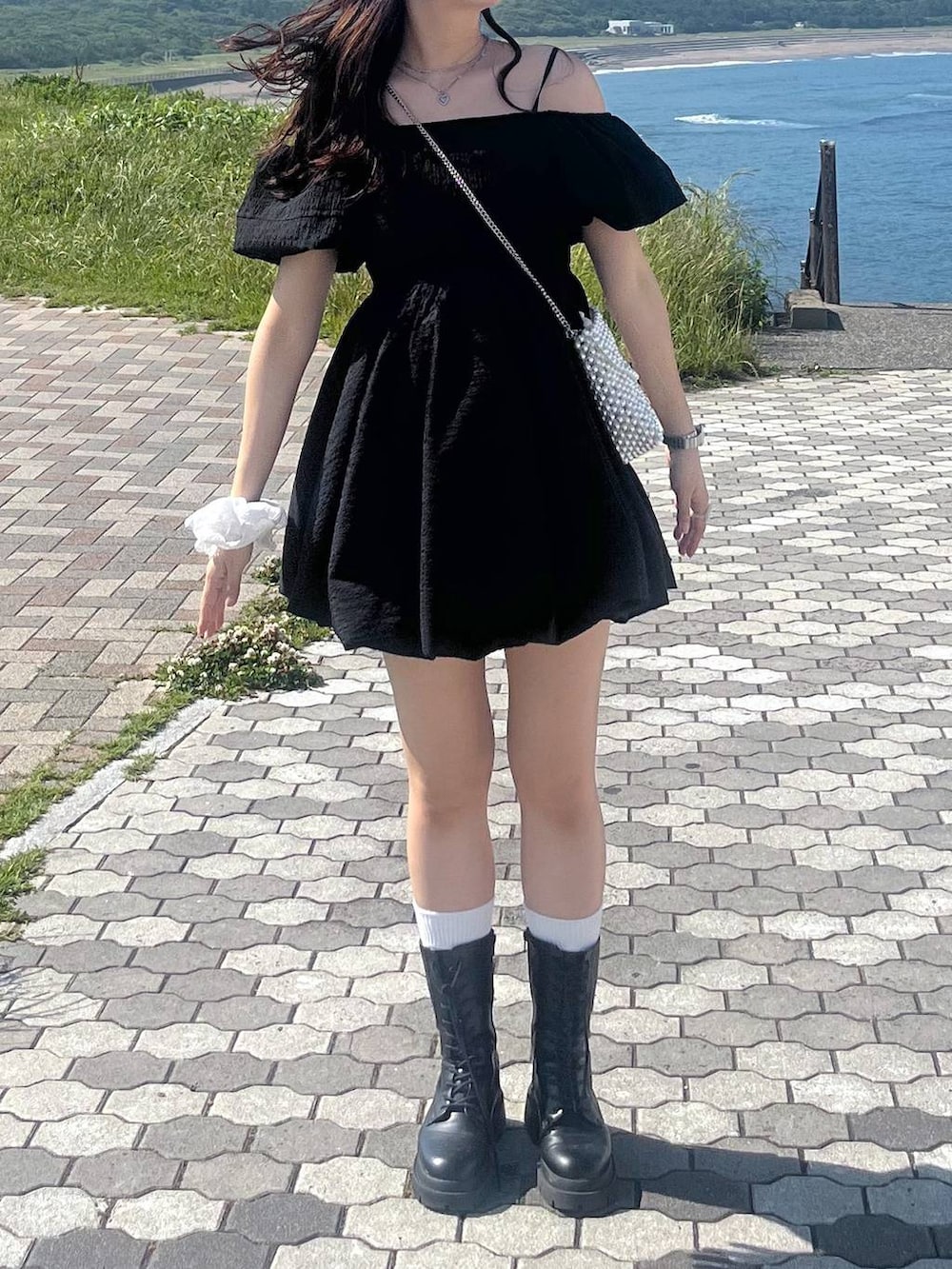 ホワイト系のキャミソール、ブラック系のワンピース、ブラック系のブーツを着用したレディースの夏コーディネートの5枚目の写真